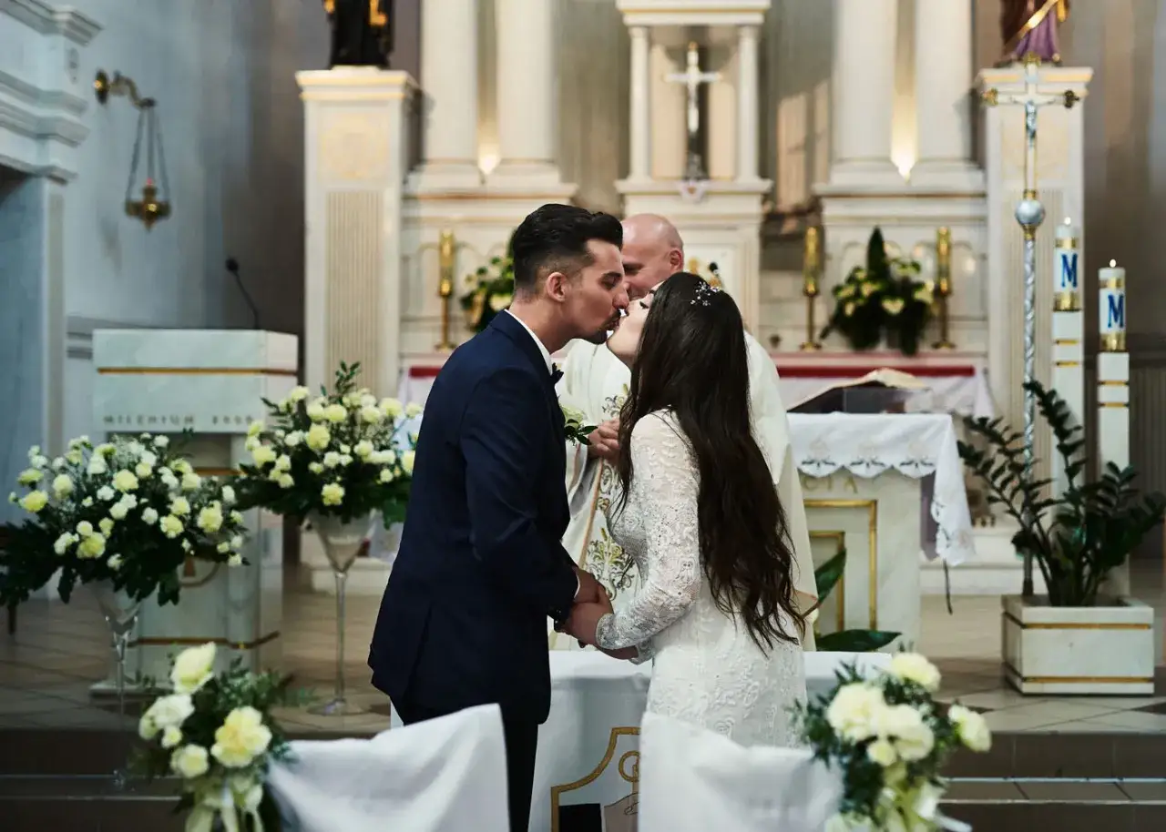 Para młoda całuje się podczas ceremonii w kościele. To ich ślub jednostronny, pełen miłości i nadziei na wspólną przyszłość.