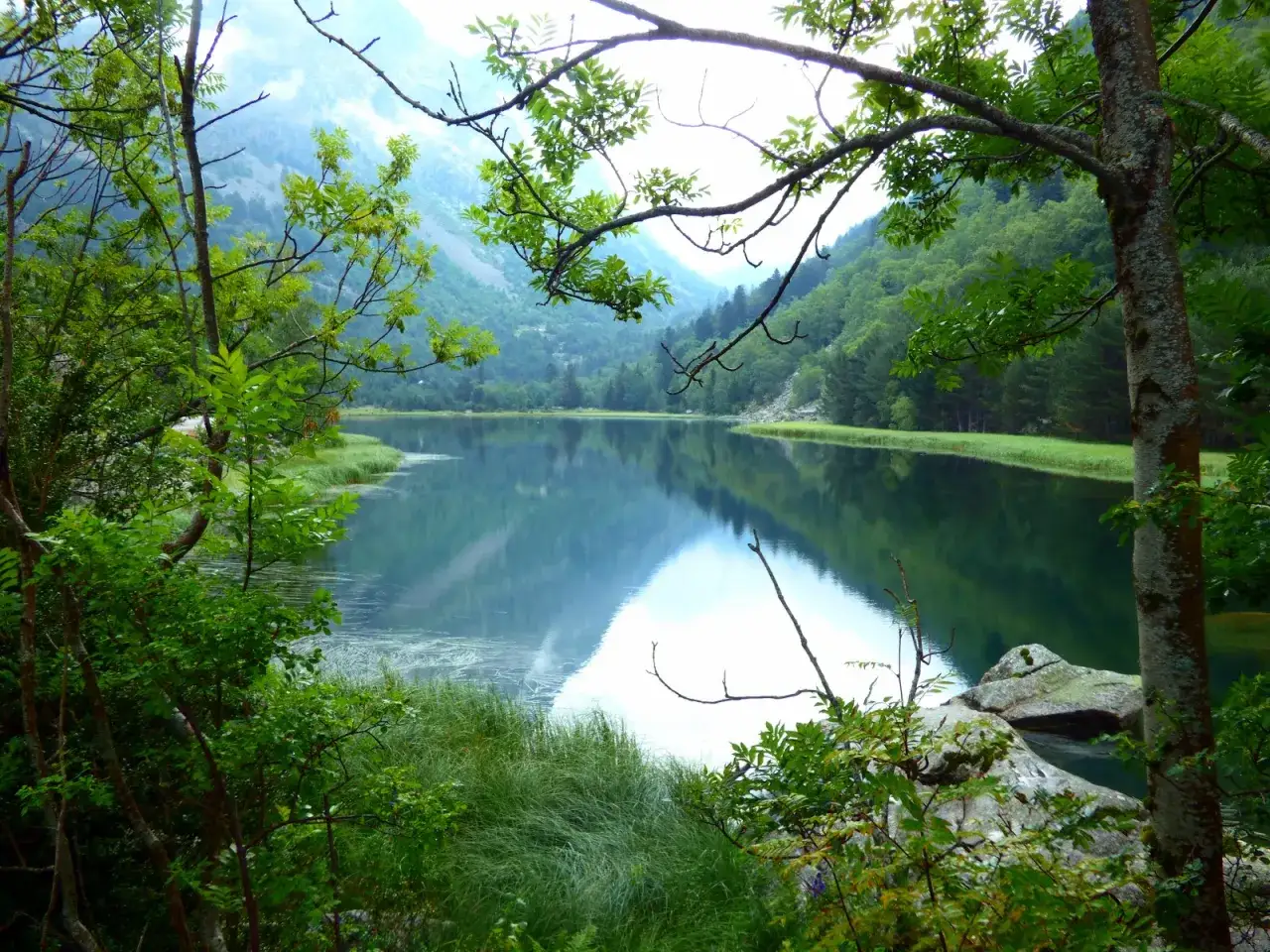 Un sereno estany de llebreta, con monta&ntilde;as verdes reflejadas en sus aguas tranquilas.