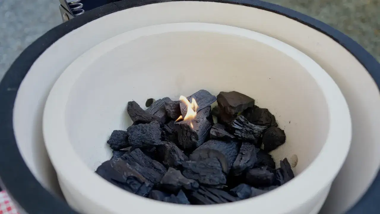 Charbon de bois s'allumant dans un kamado, pr&ecirc;t pour une cuisson parfaite.