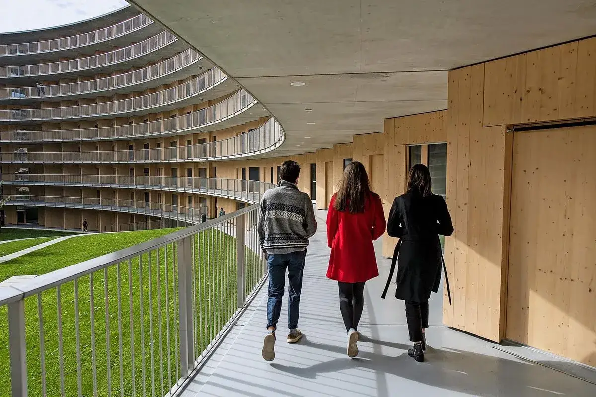 Trois étudiants marchent dans un couloir moderne de l'université de Genève, un bâtiment primé pour son architecture.