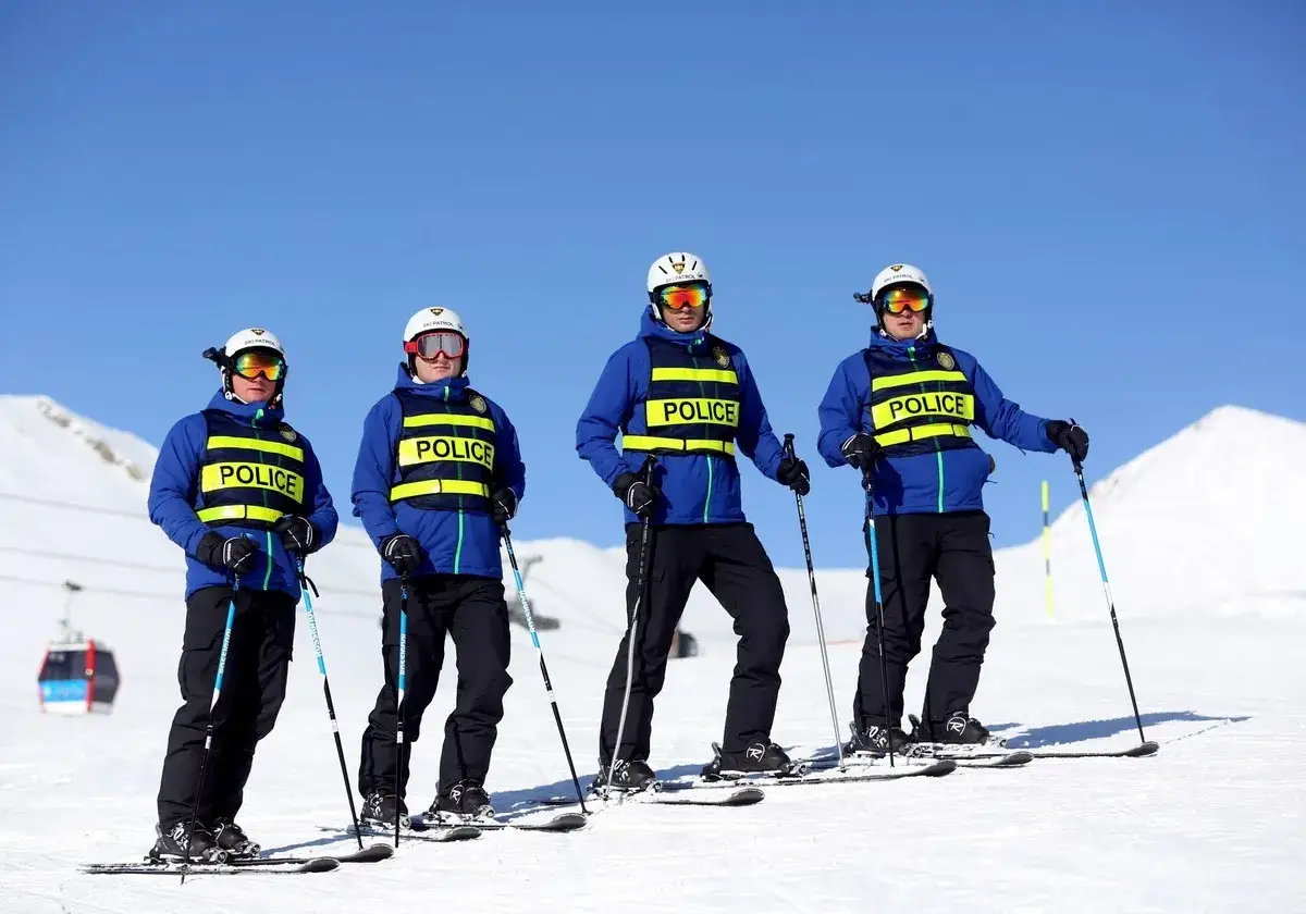 Quatre policiers à ski, portant des vestes jaunes 