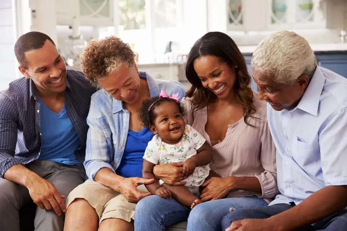 Familia multigeneracional sonríe a un bebé, celebrando los diversos tipos de lactancia y el amor familiar.