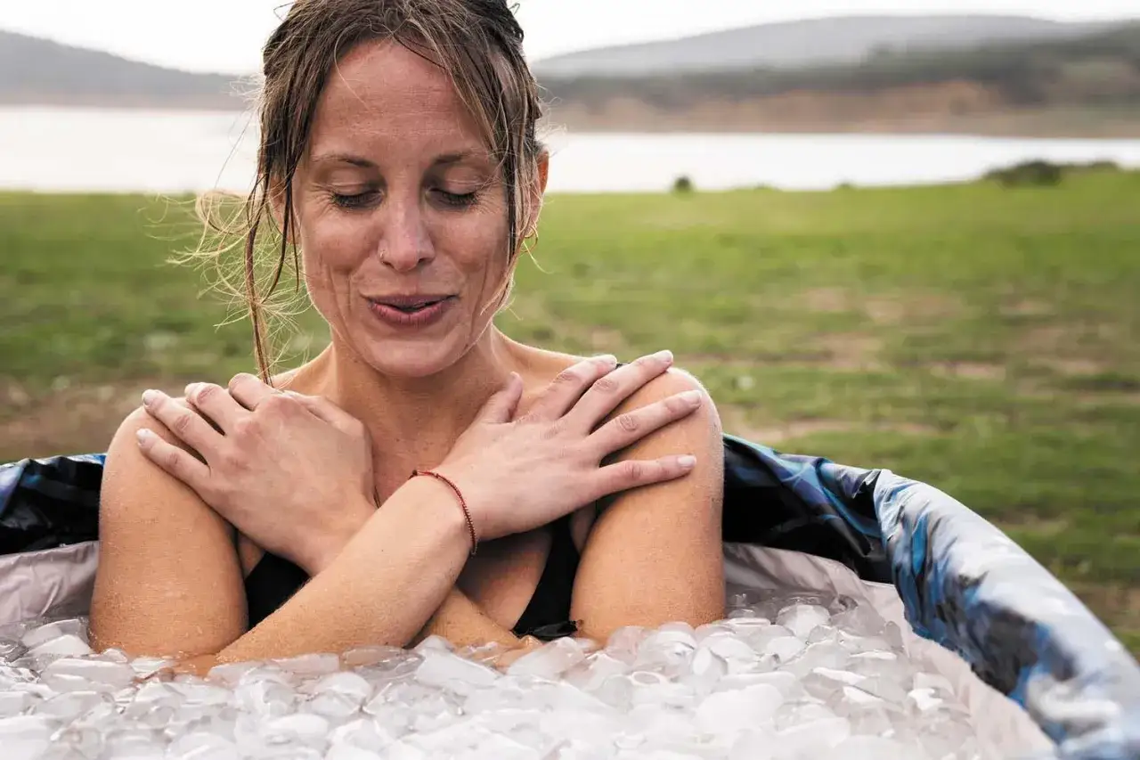 Frau genie&szlig;t Eisbad im Freien. Sie fragt sich, ob Eisbaden gesund ist, w&auml;hrend sie sich in Eisw&uuml;rfeln abk&uuml;hlt.
