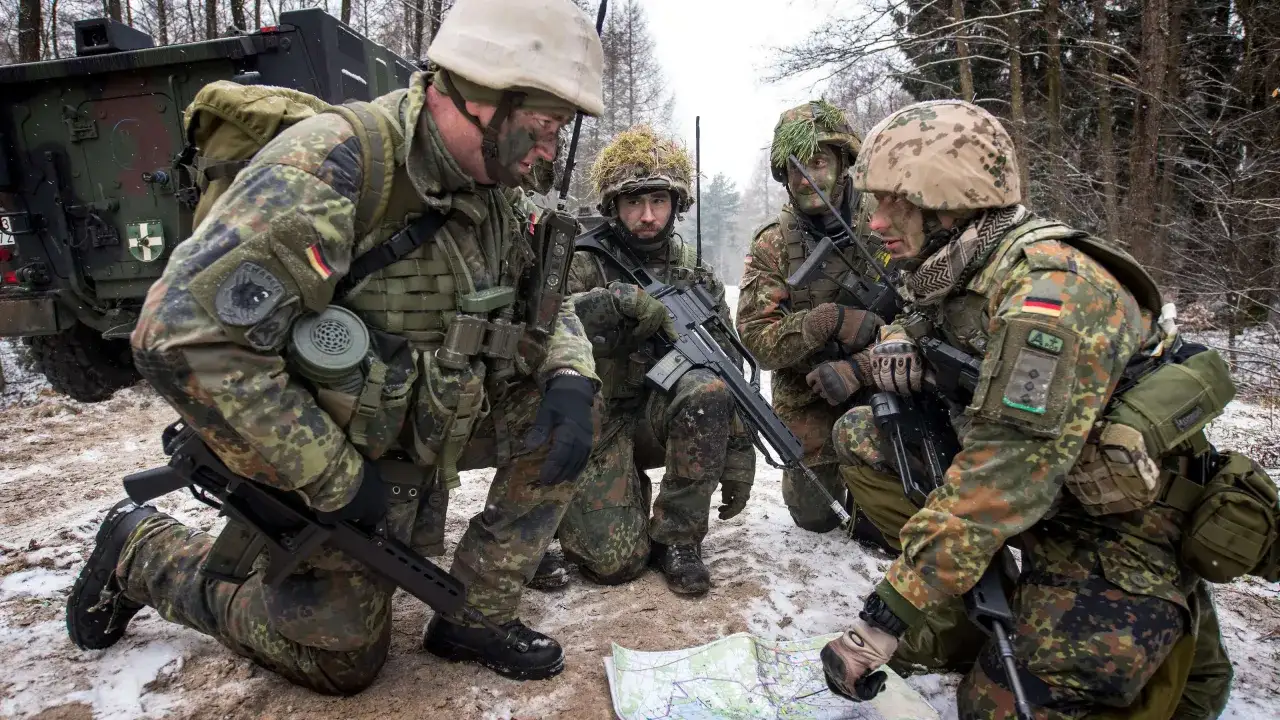 Vier Soldaten der Bundeswehr, darunter ein Fachoffizier, besprechen im Winterwald eine Karte.