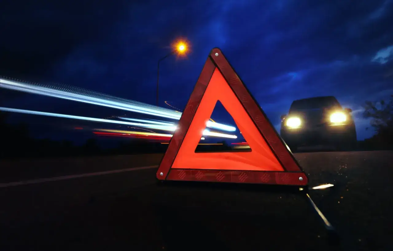 Tri&aacute;ngulo de emergencia en carretera nocturna. Se&ntilde;al de advertencia para saber qu&eacute; hacer en caso de accidente de coche.