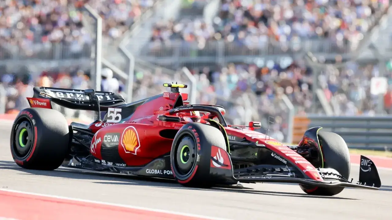 Coche de **clasificación F1** Ferrari rojo número 55 en pista, con público al fondo.