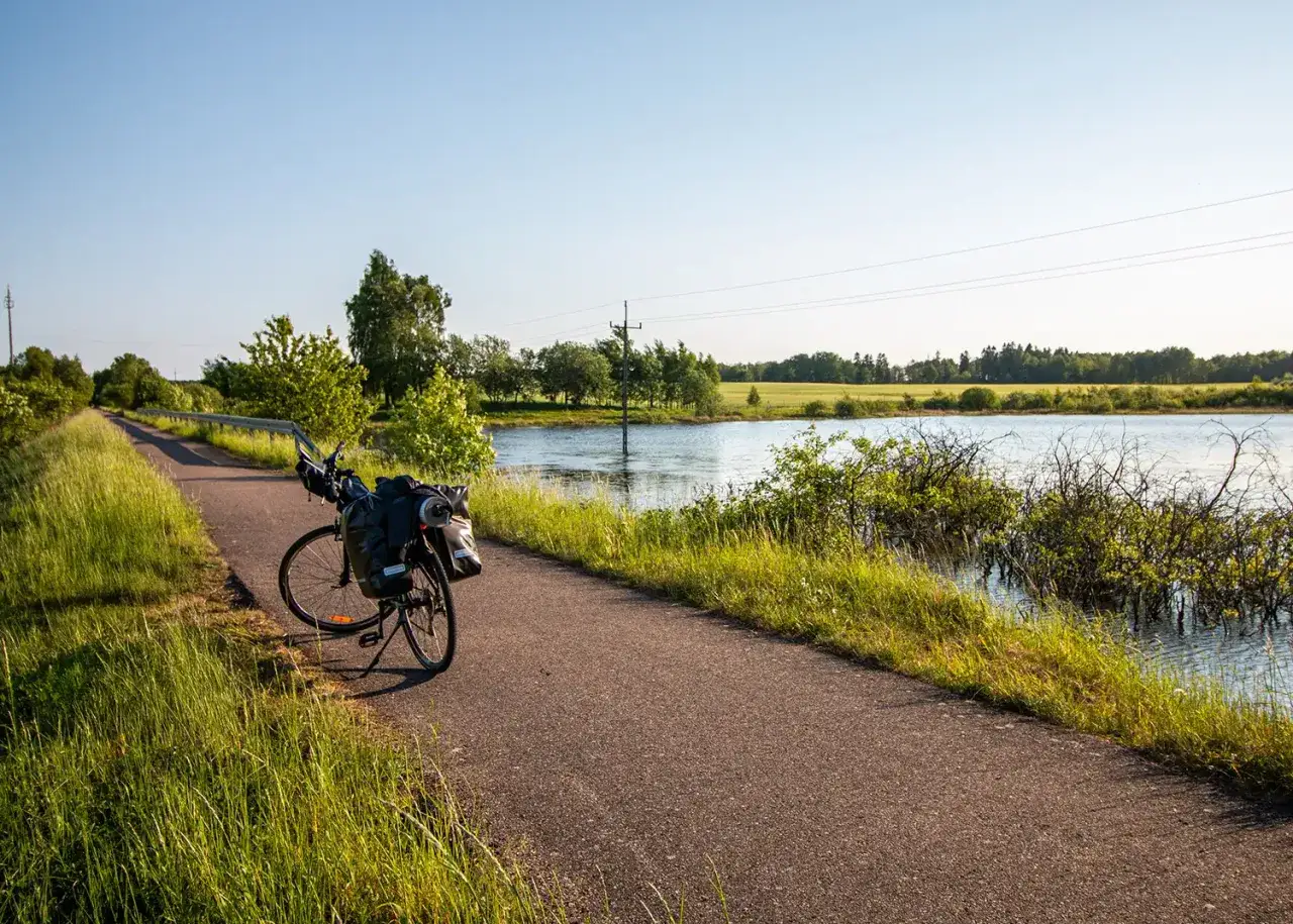 Rower z sakwami na ścieżce rowerowej w Polsce, nad spokojną wodą. Idealne miejsce na odkrywanie tras rowerowych.