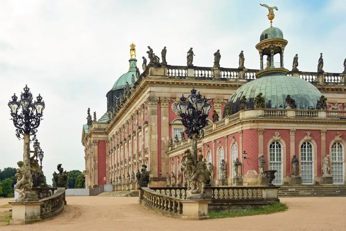 Barocke Pracht in Potsdam: Was kann man in Potsdam machen? Erkunden Sie das Schloss Sanssouci mit seinen Statuen und kunstvollen Laternen.