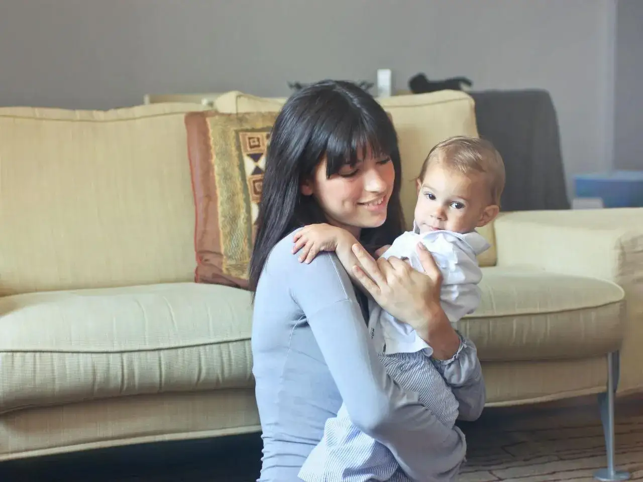 Uśmiechnięta opiekunka trzyma dziecko. Zastanawiasz się, ile bierze opiekunka do dzieci za godzinę?