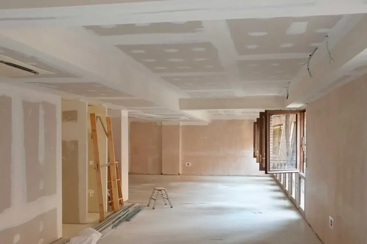 Interior en construcci&oacute;n con techos y paredes de tabiques de pladur, escaleras y ventanas abiertas.