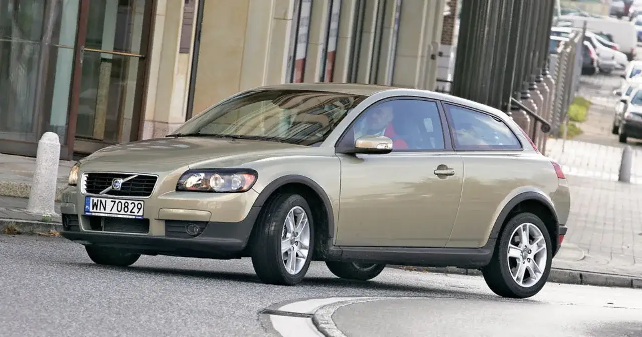 Złoty Volvo V30 z polskimi tablicami rejestracyjnymi jedzie po miejskiej ulicy.