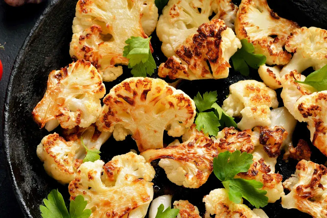 Coliflor al horno dorada y tierna, con bordes caramelizados y perejil fresco. Un plato sencillo y delicioso.