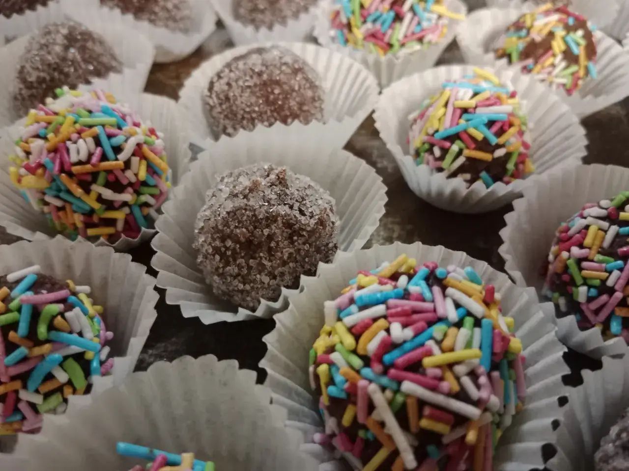 Schokokugeln rezept: Bunte Schokokugeln mit Streuseln und einige in Zucker gew&auml;lzt, in Papierf&ouml;rmchen arrangiert.