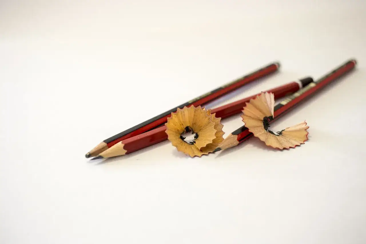Tres lapiceros rojos con virutas de madera, listos para escribir o dibujar.