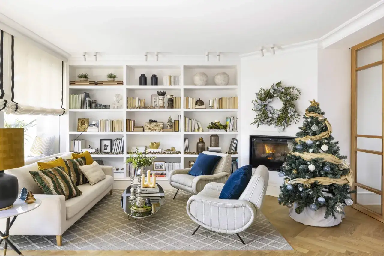 Acogedor salón de navidad con chimenea encendida, árbol decorado y estanterías llenas de libros y adornos.