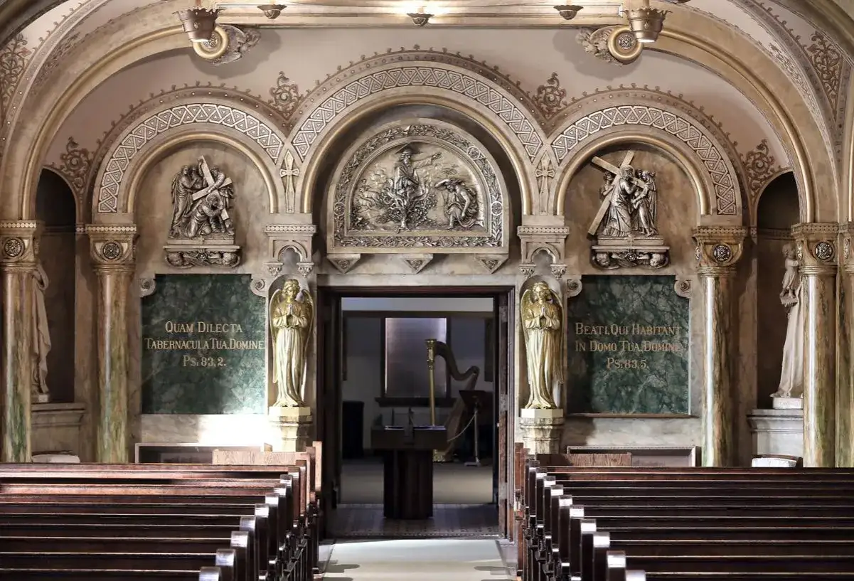 Interior of St. Rose of Viterbo convent chapel, featuring ornate arches, religious reliefs, golden angels, and pews.