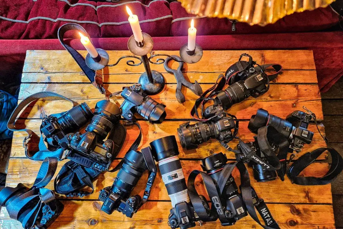 Na drewnianym stole, przy świecach, leży kolekcja profesjonalnych aparatów. To marzenie każdego fotografa, być może nawet najdroższy aparat fotograficzny.
