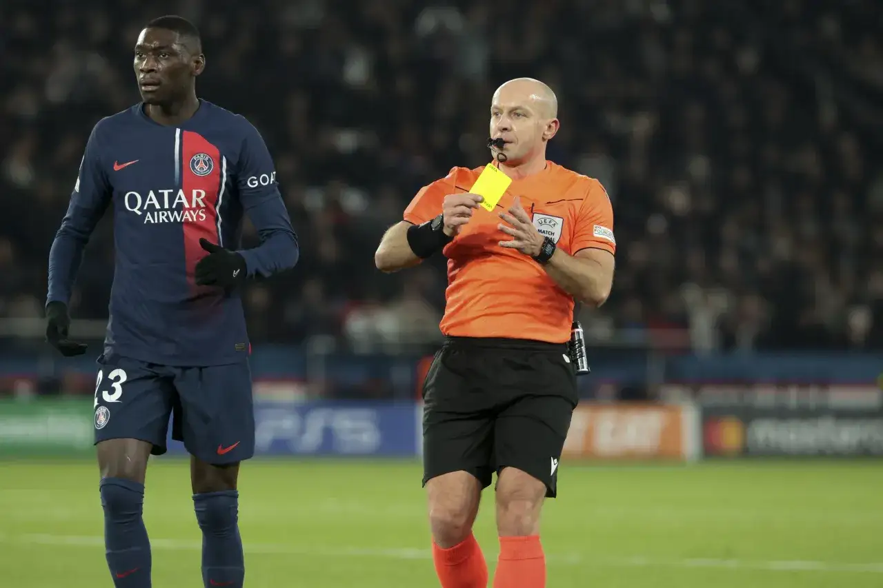 Sędzia pokazuje żółtą kartkę, co oznacza ostrzeżenie dla zawodnika PSG.