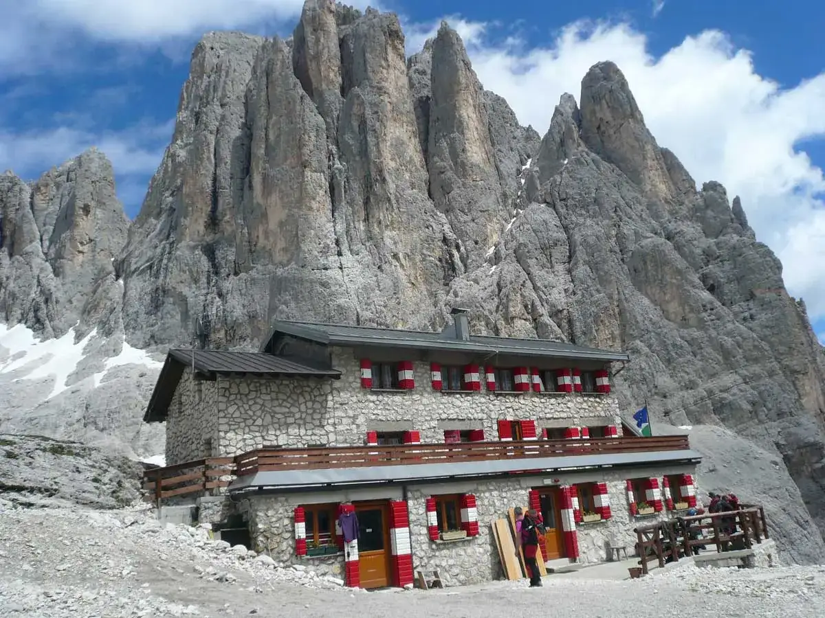 Rifugio alpino con imponenti vette dolomitiche sullo sfondo, ideale per un trekking di 5 giorni.