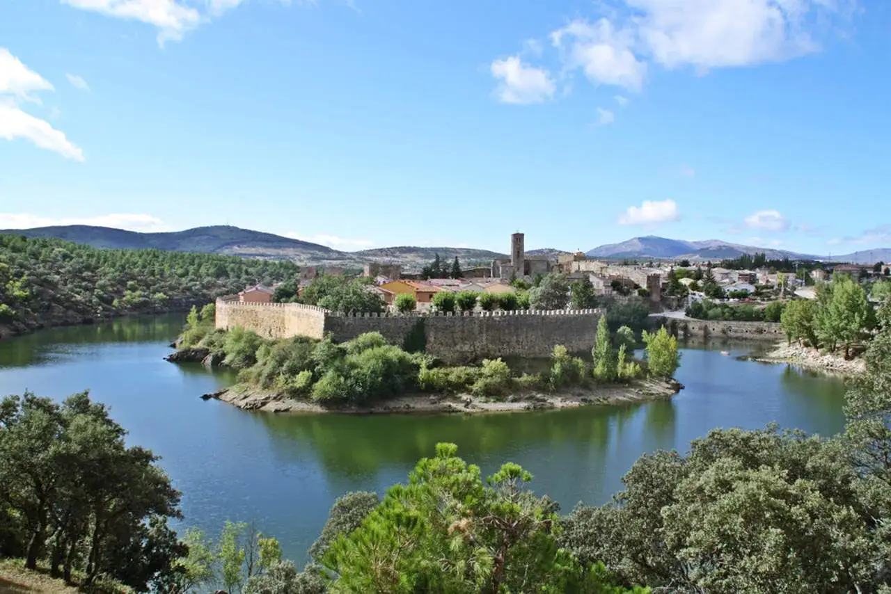 Castillo medieval en un lago, rodeado de vegetaci&oacute;n. Un ejemplo de los bellos pueblos de Madrid.