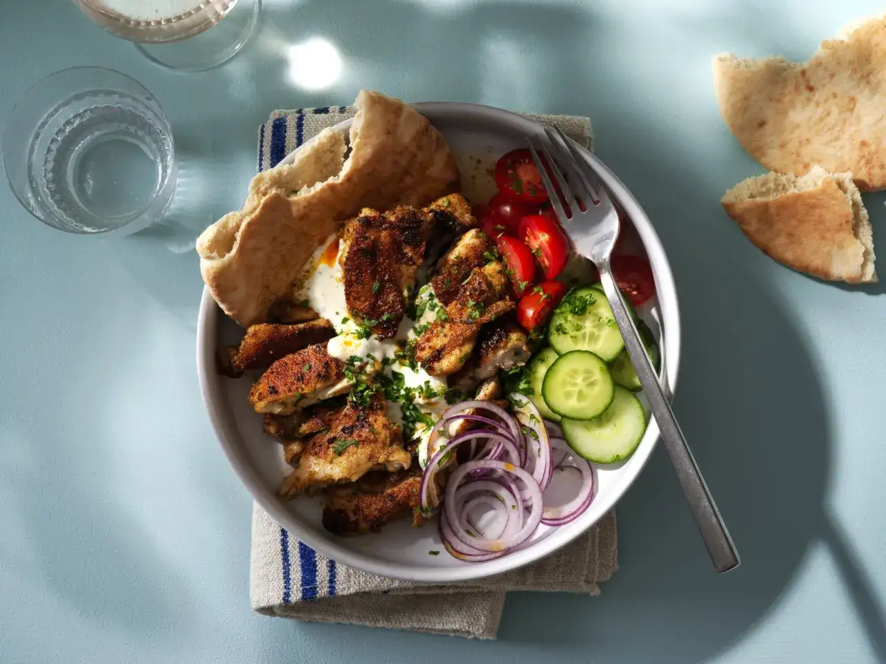 En tallrik med kyckling shawarma, pitabr&ouml;d, tomater, gurka och r&ouml;dl&ouml;k. Ett perfekt shawarma recept f&ouml;r en snabb och god middag.