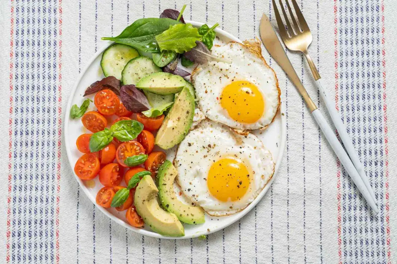 Piatto con uova fritte, avocado, pomodorini e insalata. Ideale per colazioni proteiche veloci e nutrienti.
