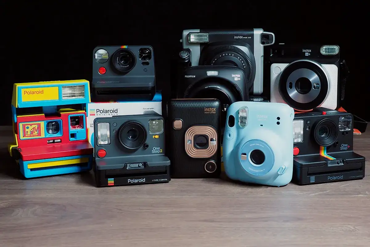 Kolekcja aparatów natychmiastowych, w tym różne modele Instax i Polaroid. Zastanawiasz się, co to Instax? To właśnie te aparaty!