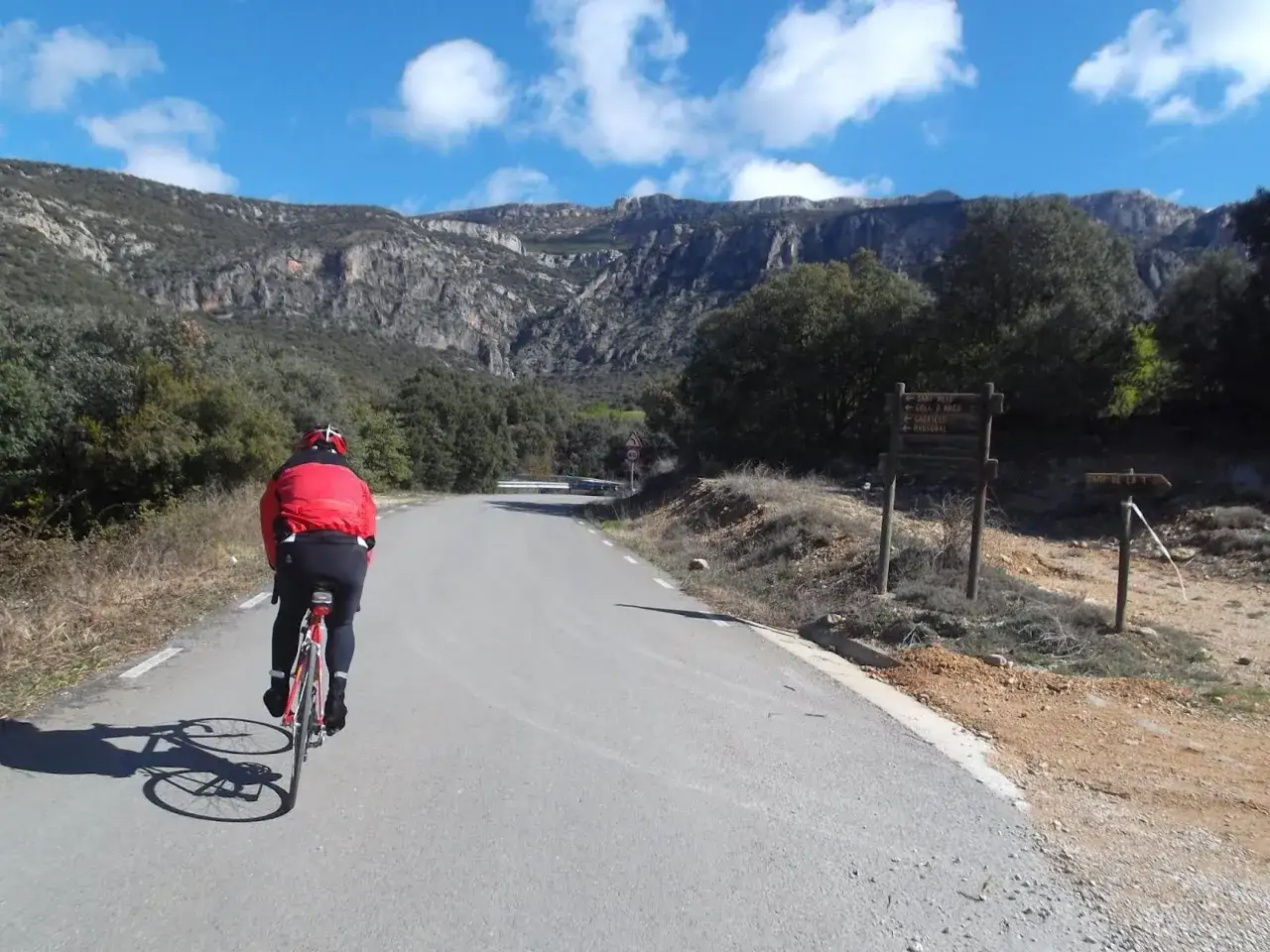 Ciclista en ruta de gravel por el Pirinexus, con montañas rocosas y cielo azul.