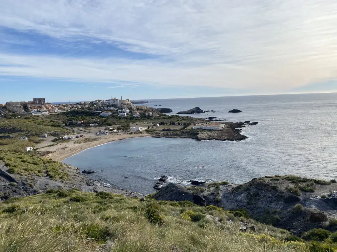 Vista de la costa y el mar Mediterráneo desde la ruta Calblanque. Un pueblo costero se asoma entre la vegetación y las rocas.