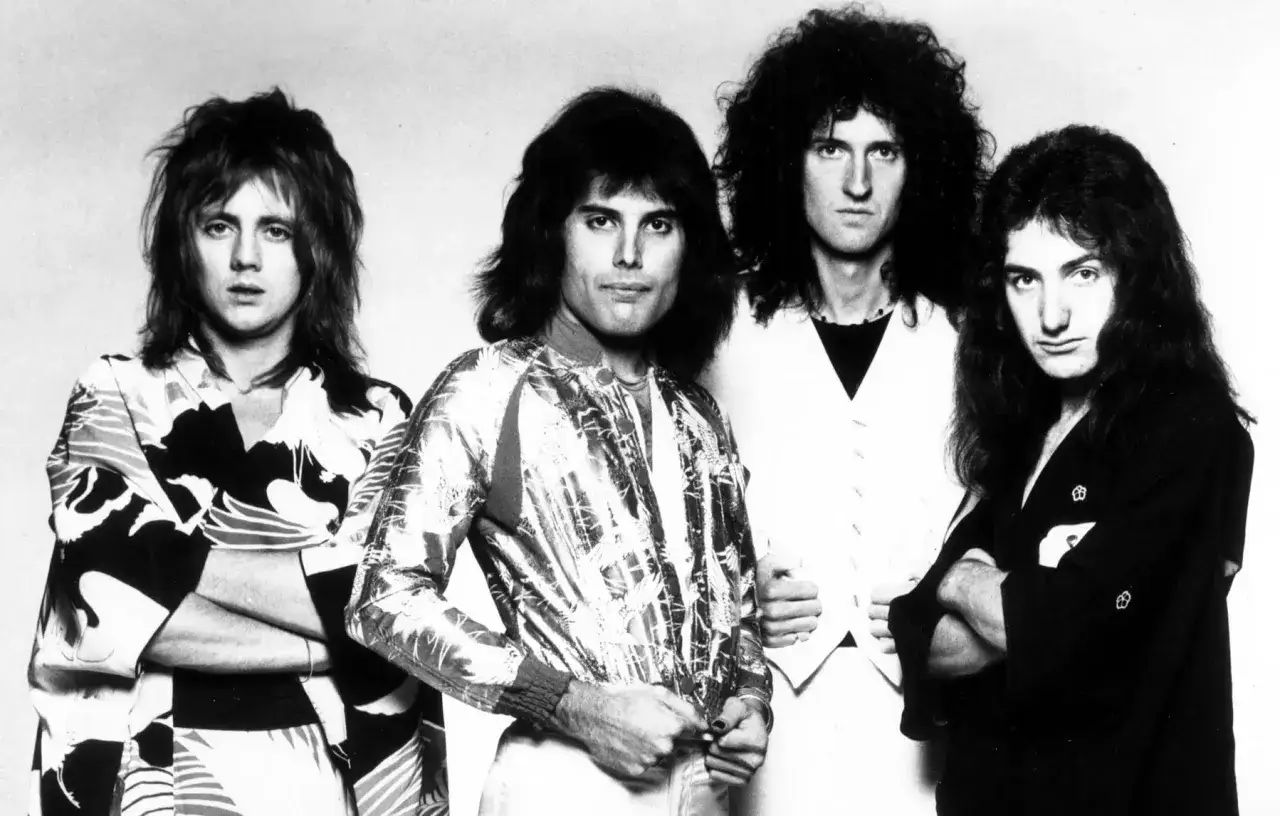 Freddie Mercury zespół Queen w klasycznych strojach. Czterech muzyków pozuje do zdjęcia, każdy w unikalnym stylu.