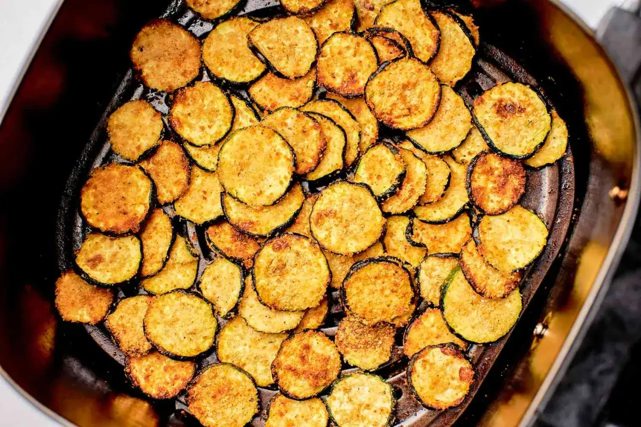 Rodajas doradas de calabacín en freidora de aire, crujientes y listas para disfrutar.