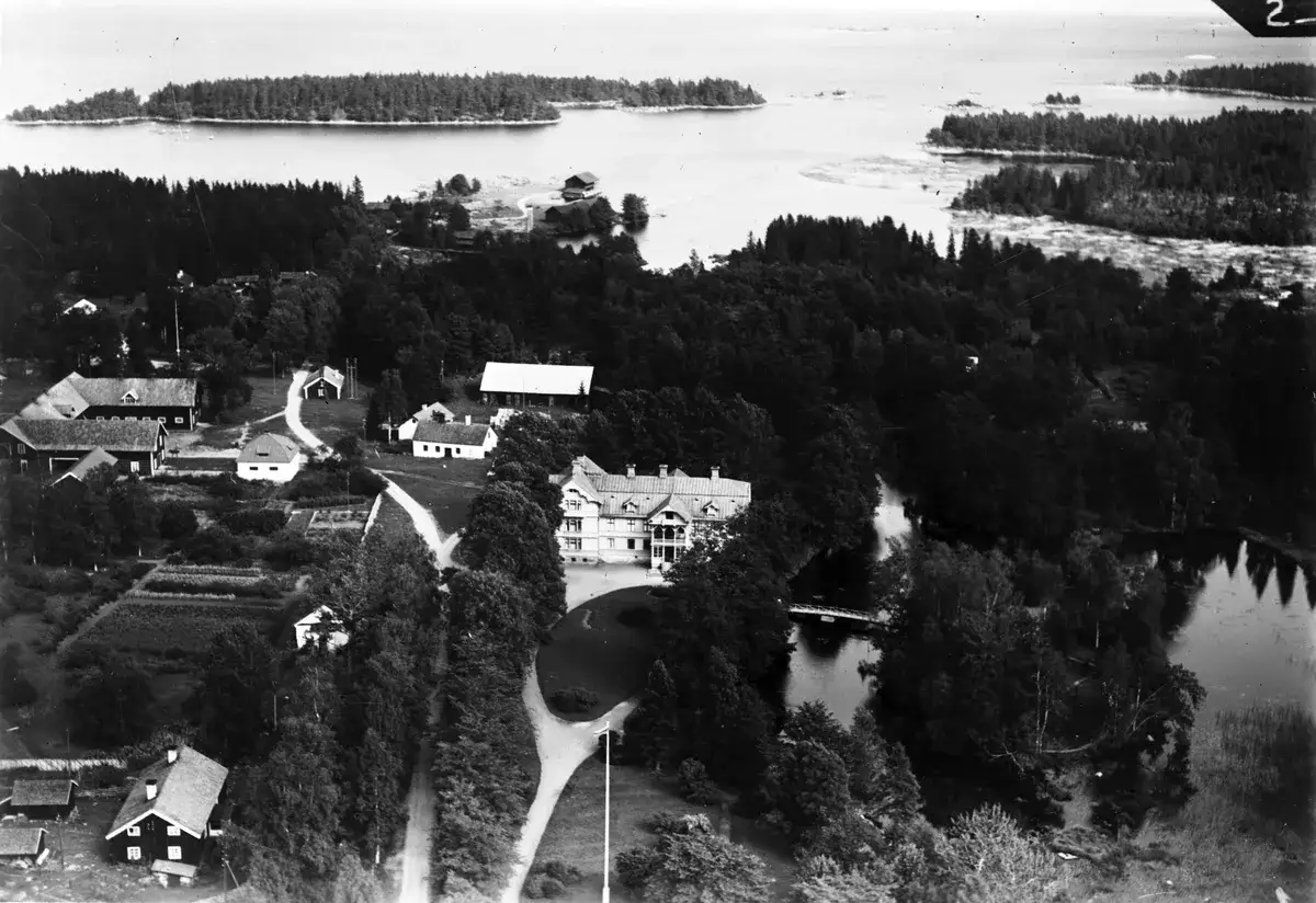 Luftfoto &ouml;ver L&aring;ngvinds bruk med herrg&aring;rd, ekonomibyggnader och omgivande skog och vatten.