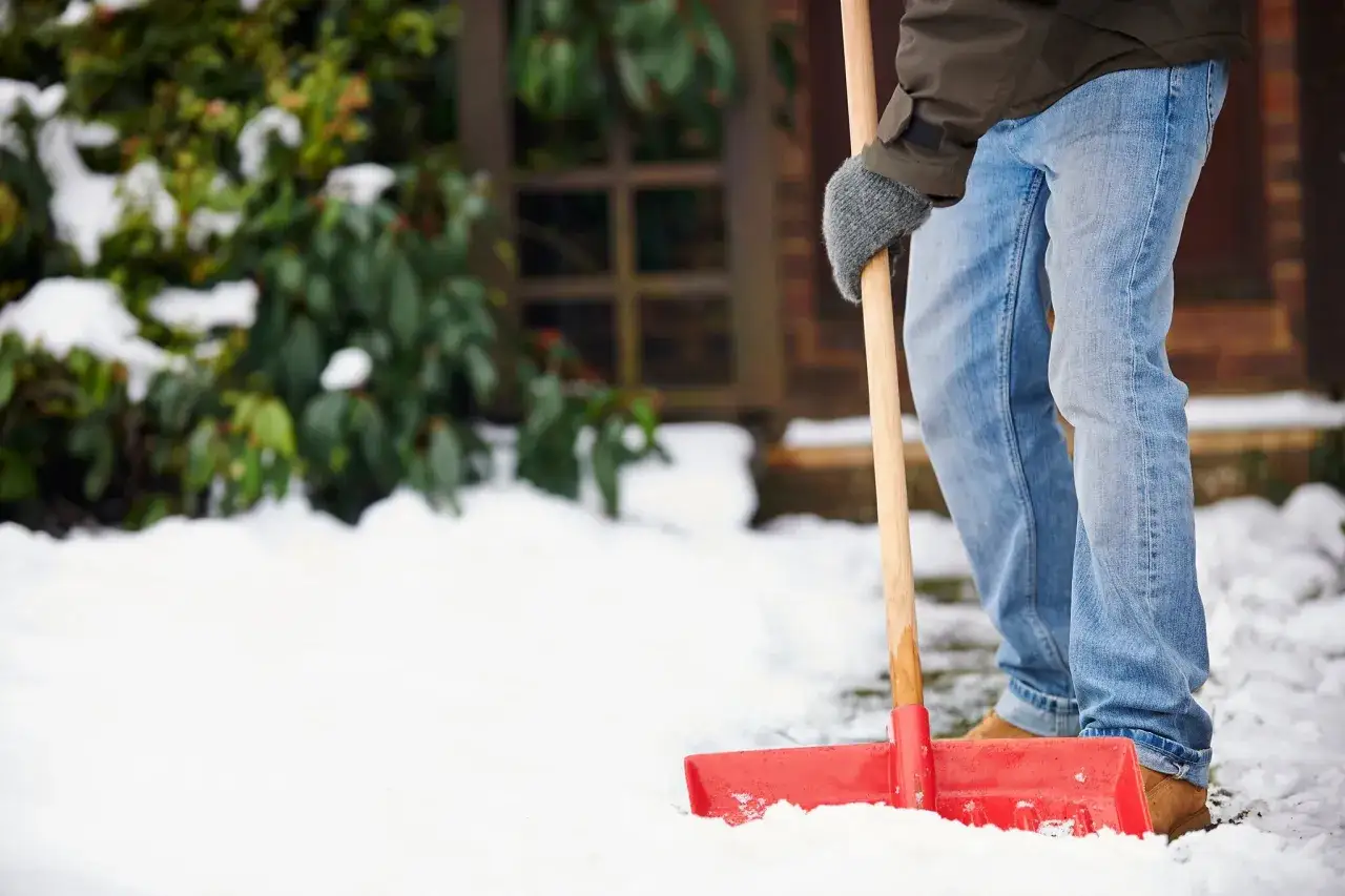 Mann schaufelt Schnee, um dem Winterdienst-Gesetz nachzukommen.