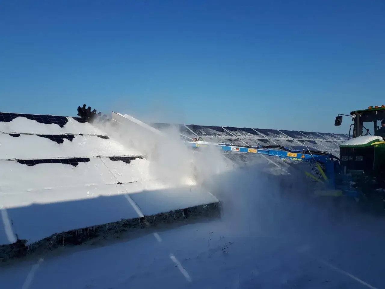 Traktor med borste som hj&auml;lper till att skotta solpaneler fr&aring;n sn&ouml;.