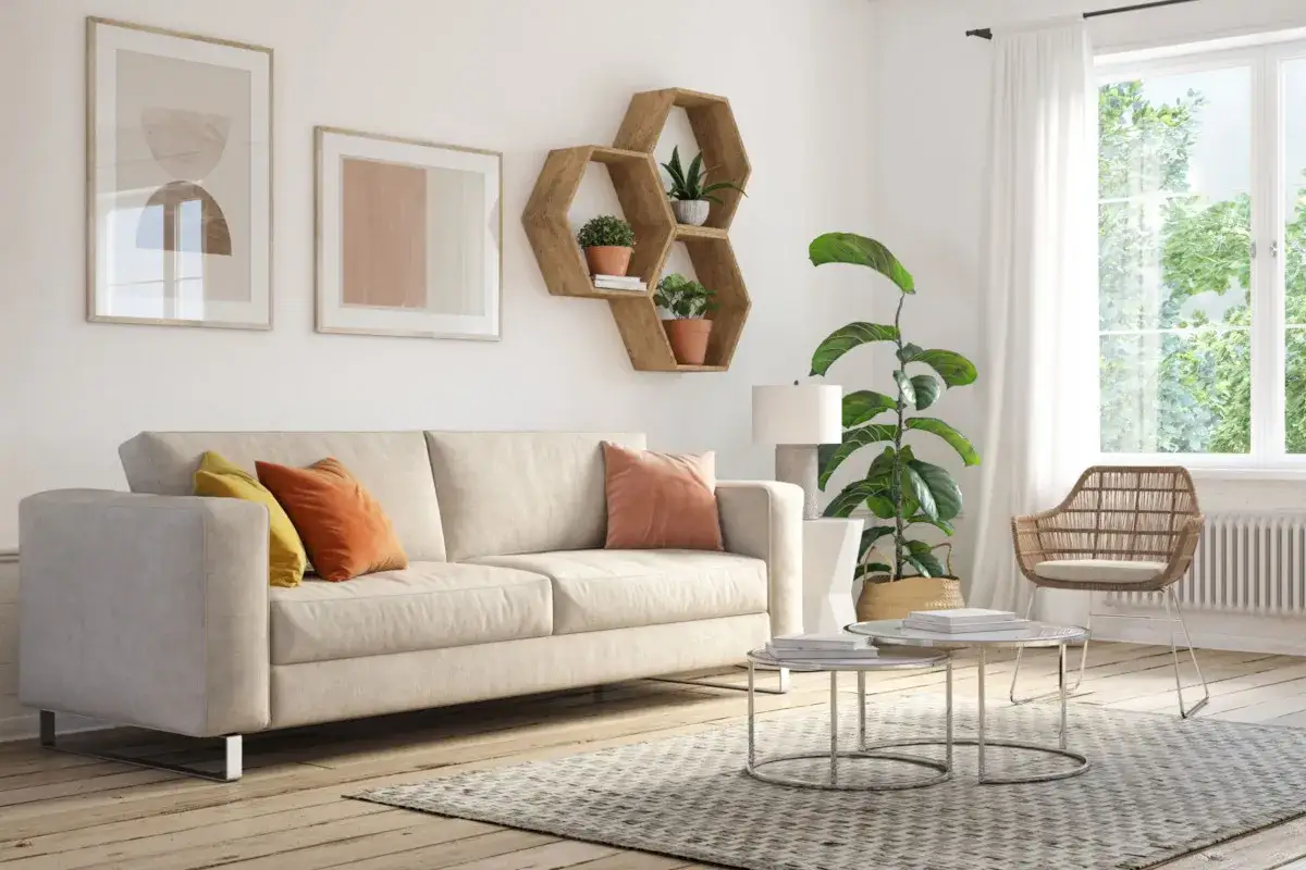 Jasny salon z beżową kanapą, kolorowymi poduszkami i geometrycznymi półkami. Inspiracja, jak umeblować mały pokój, by był przytulny i funkcjonalny.
