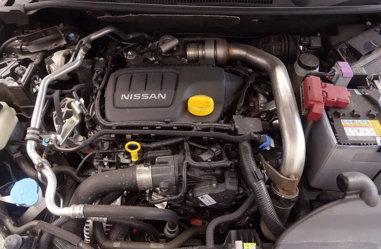 Silnik Nissana Qashqai J10 z widocznym logo NISSAN, żółtym korkiem oleju i elementami układu dolotowego.
