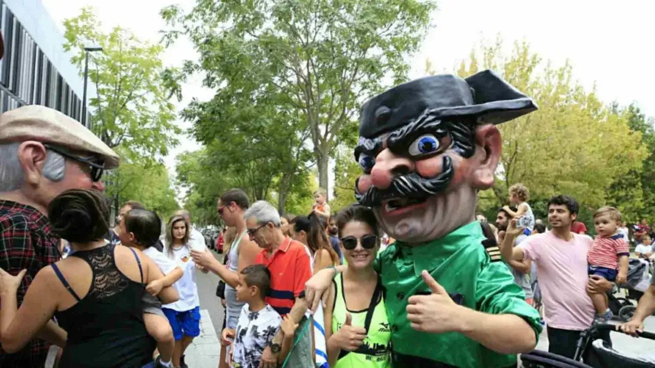 Gigantes y cabezudos animan las fiestas San José Zaragoza. Gente sonriente, niños y un personaje con gran cabeza disfrutan del ambiente festivo.