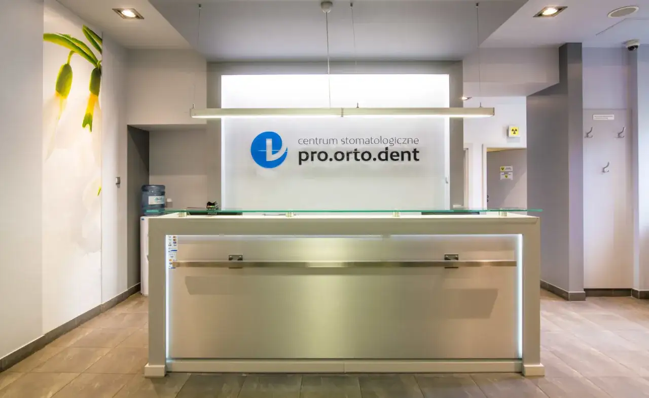 Recepcja gabinetu stomatologicznego pro.orto.dent z logo i ozdobną grafiką na ścianie.