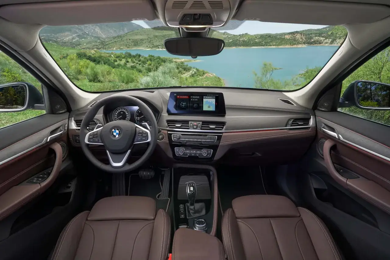 Wnętrze BMW X1 2025 z brązową skórzaną tapicerką i widokiem na jezioro.