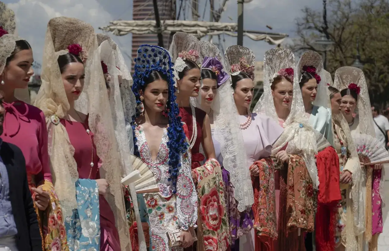 Desfile de mujeres con trajes de flamenca y mantillas, un evento 