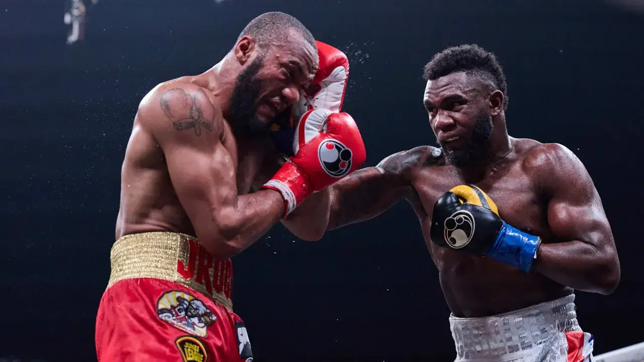 Carlos boxer lands a powerful punch, his opponent recoiling from the impact. Sweat flies as the fight intensifies.