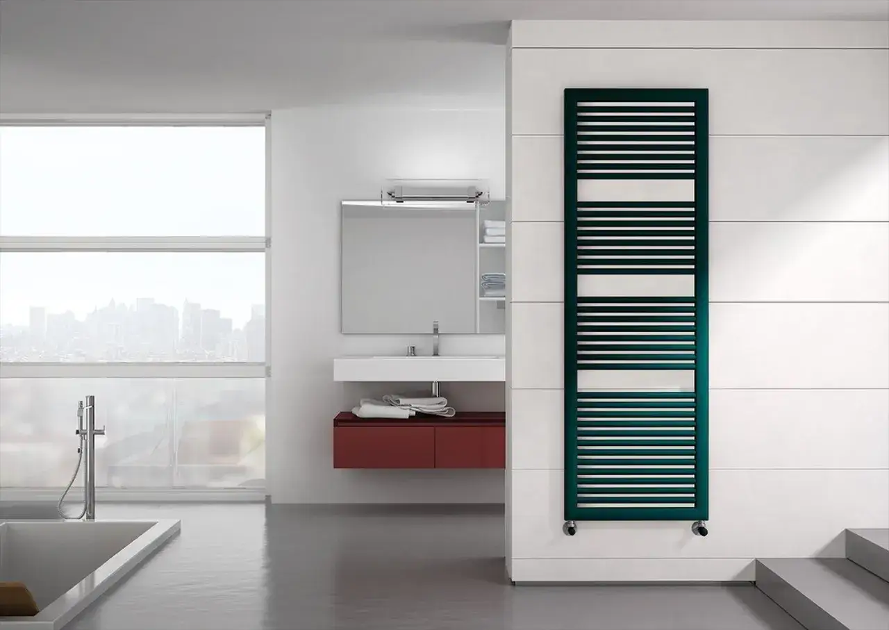 Elegante termoarredo Irsap verde petrolio, con un design moderno a listelli orizzontali, si integra perfettamente in un bagno minimalista con vista sulla citt&agrave;.