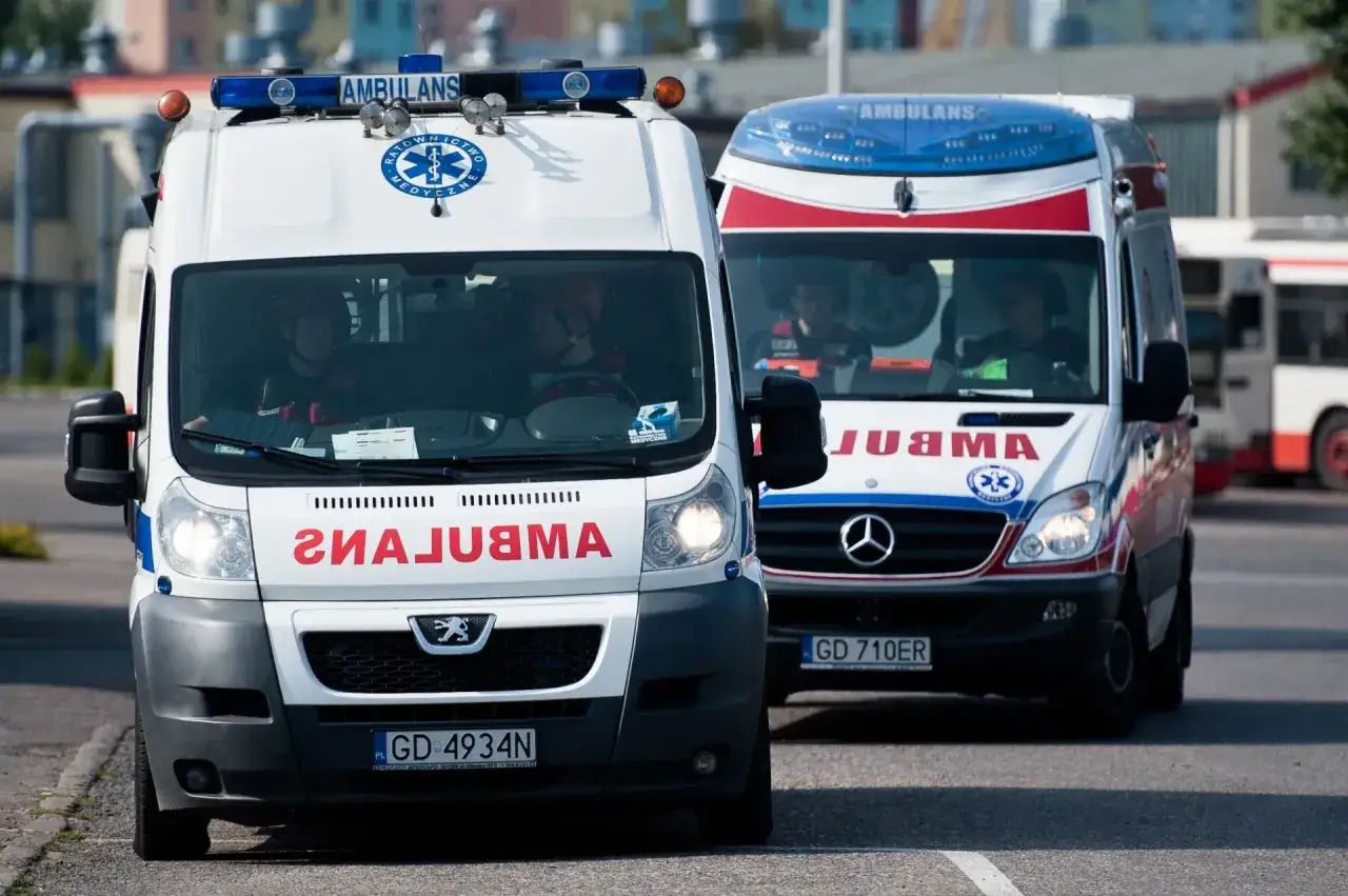 Dwa pojazdy uprzywilejowane, ambulanse, jadące obok siebie. Jeden z nich ma na masce logo Peugeota, drugi Mercedesa.