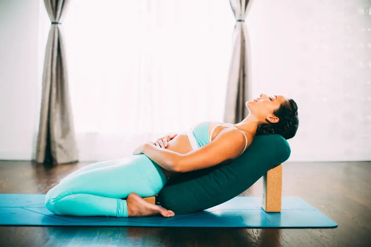 Mujer embarazada en postura de yoga restaurativo, ideal para el yoga embarazo primer trimestre.