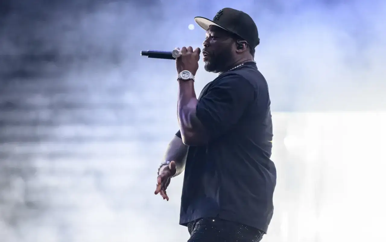 50 Cent w Polsce, na scenie, z mikrofonem w dłoni, w czapce i z błyszczącym zegarkiem.