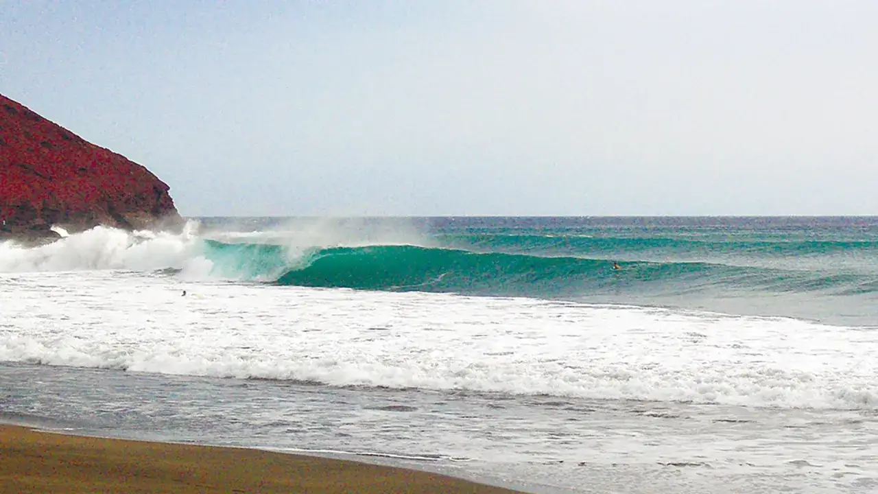 Gr&uuml;ne Wellen brechen an der K&uuml;ste von La Gomera. Ein Surfer wartet auf die perfekte Welle.