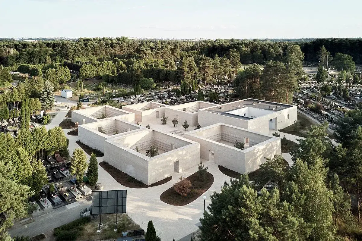 Nowoczesne kolumbarium otoczone cmentarzem i lasem. Architektura tworzy spokojną przestrzeń pamięci.