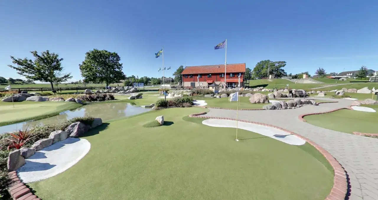 En solig dag på slussen minigolf i Sverige. Banan slingrar sig förbi vatten, stenar och sandhinder.