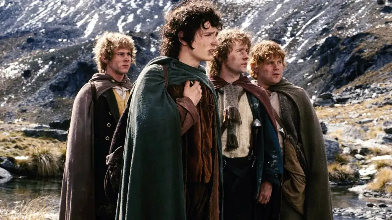 Czterech hobbitów w pelerynach, w tym Frodo, wyrusza w podróż. To scena z 