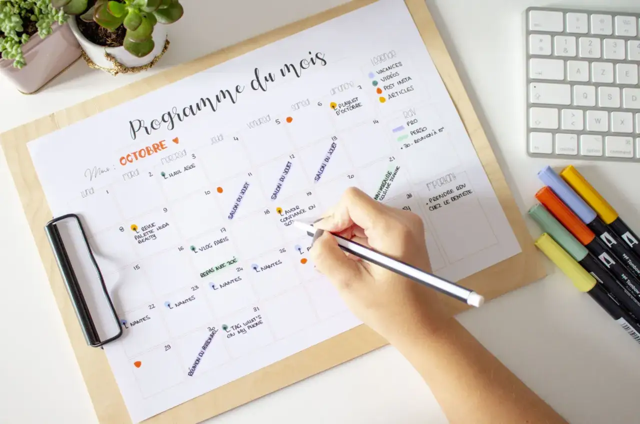 Une main &eacute;crit sur un calendrier mensuel, planifiant l'exercice et les rendez-vous. Id&eacute;al pour l'exercice planification adulte.